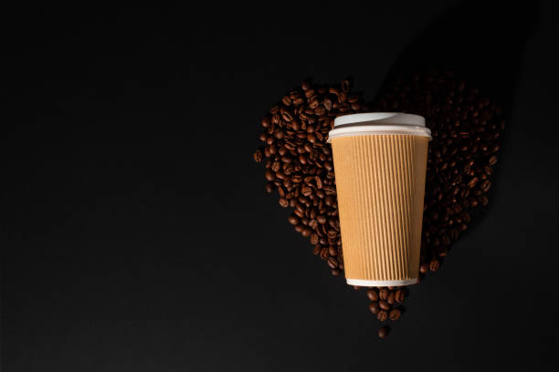 istock Paper cup of coffee with coffee beans on black background 1282909498