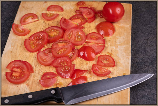 istock Sliced tomatoes on wooden cutting board with knife lying on side 1282910152