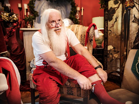 Santa Claus getting dressed in his study to do a Christmas video conference. He is getting ready for Christmas season.