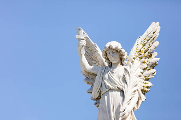 istock Angel, old statue of angle with cross, blue sky background with copy space 1282911977