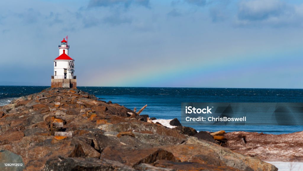 The Wisconsin Point Light is a lighthouse located near Superior on Wisconsin Point Rainbow in the background A rainbow forms as a storm clears the area at Superior Entry Lighthouse close to the Minnesota Wisconsin border USA Michigan Stock Photo