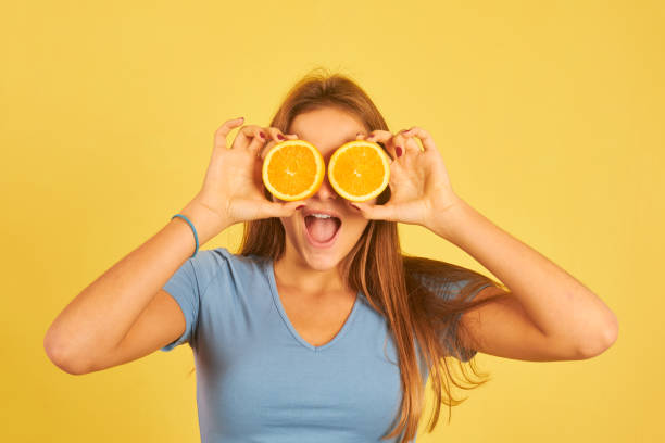 istock happy young woman using oranges as glasses 1282914865