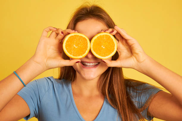 istock happy young woman using oranges as glasses 1282914918