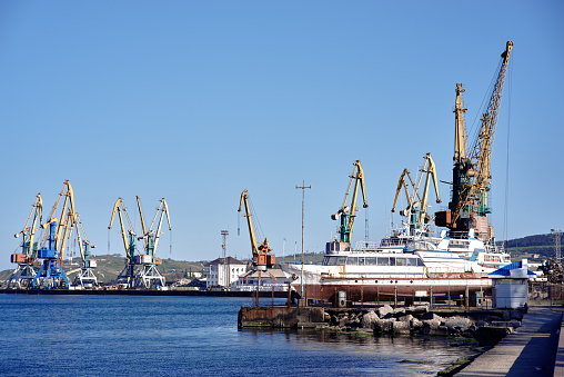 Port, crane, pier, blue sky. Heap of metal garbage for recycling. Feodosia, Crimea