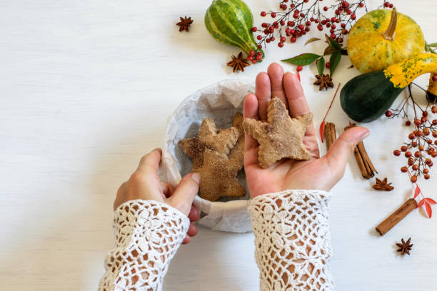 istock Female hands holding cinnamon star cookie, Halloween pumpkin on the table. 1282916137