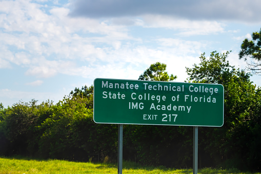 Tampa, USA - April 27, 2018: Florida highway road with sign for Manatee Technical College IMG Academy exit with sky