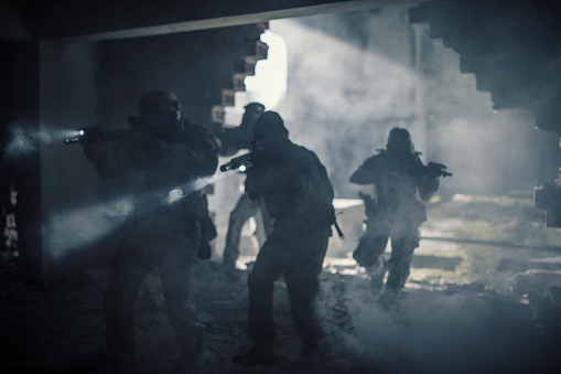 Group of soldiers in camouflage uniforms hold weapons with patrol missions at night