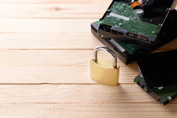 Photo of hardware data protection technology concept. stack hard drive discs and golden padlock over wooden background. studio shot. privacy data conceptual