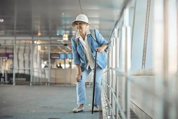 Front view of a female tourist with a walking cane experiencing a sudden knee pain at the airport