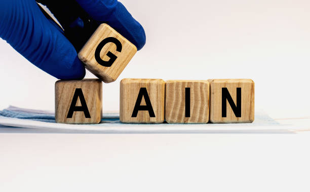 istock Text AGAIN made from wooden cubes. Hands in a blue glove. 1282932813