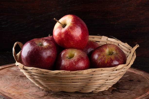 istock Red apples in basket with wooden background. 1282936286