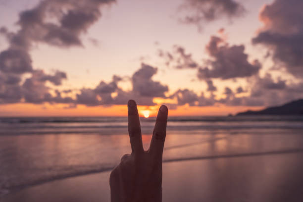 istock Woman hand do peace out with sunset beach background. 1282936420