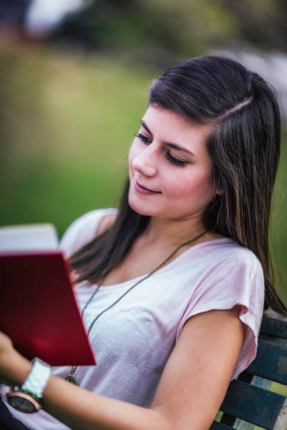 istock Relaxing young woman reading book on a university campus 1282939509
