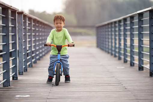 A little boy learning to ride a bicycle outdoors