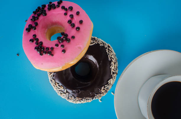 istock Black and Pink round donut at bright blue background with coffee glass 1282955909