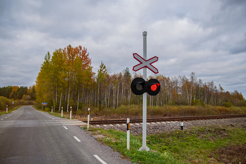 Railway transportation safety symbol. Countryside in south Estonia, cloudy summer day. Selective focus.