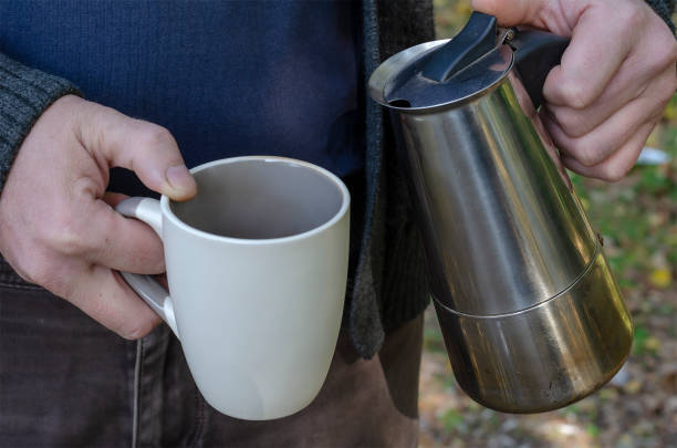 istock Man pours brewed coffee into cup from an outdoor geyser coffee maker. 1282960150