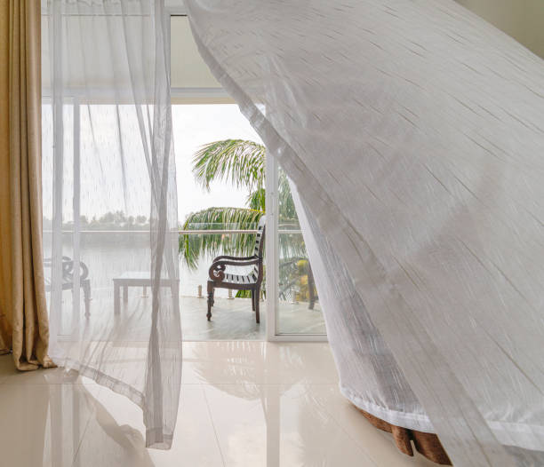istock Wind moving curtains on the open balcony window with the scenic view on a river from the modern empty hotel room. 1282963978