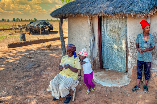 traditional African family spending time together in the front of their home, village in Botswana
