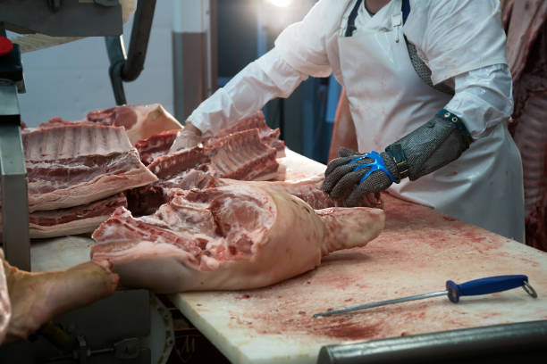 Meatman cuts freshly slaughtered meat of pork stock photo