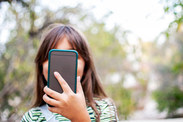 istock Littel girl using mobile phone outdoors 1282970363