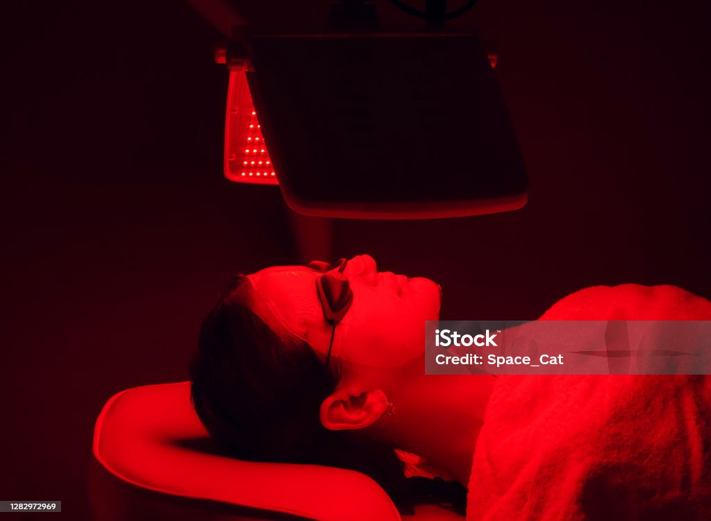 Young woman having red LED light facial therapy treatment in beauty salon. Beauty and wellness Young woman having red LED light facial therapy treatment in beauty salon. Beauty and wellness concept Alternative Therapy Stock Photo