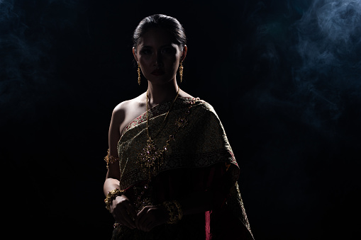 Silhouette of Woman in Thai Traditional Costume, antique old fashion clothes. Low Exposure Dark background