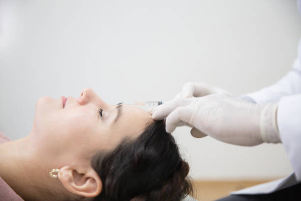 Young woman getting beauty facial injections in salon. Beautician makes cosmetic injection into the patient frown lines. Beauty injections, mesotherapy, revitalization and rejuvenation stock photo