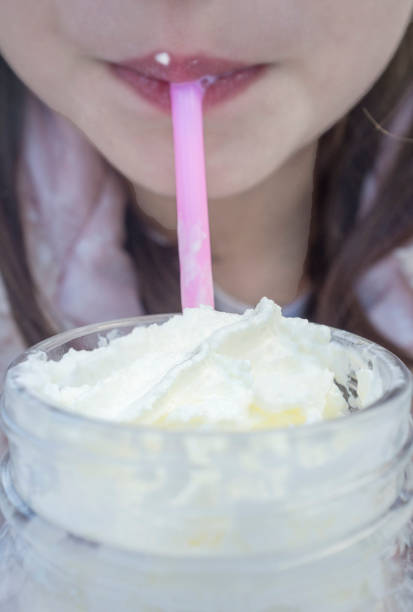 istock Little girl drinking milkshake through a pink straw 1282976232