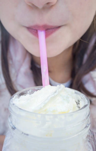 istock Little girl drinking milkshake through a pink straw 1282976239