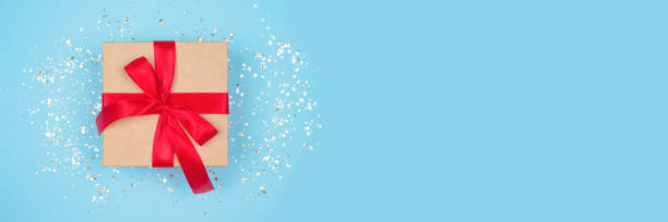 istock Festive banner - gift box with red bow on festive blue background, with golden sparkles and copyspace for your text. Flat lay style. Christmas, New Year, Valentines Day or birthday celebration concept 1282983607