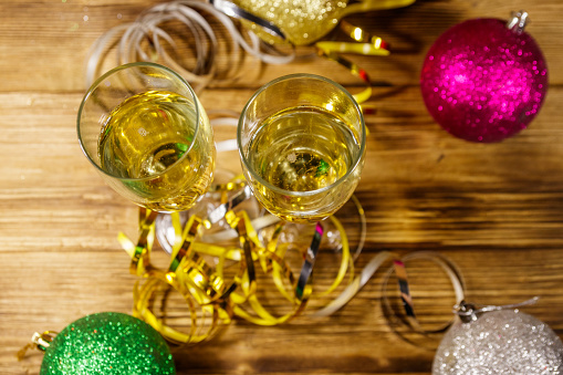 Two glasses of champagne and festive Christmas decorations on wooden table. Top view. Christmas and New Year celebration
