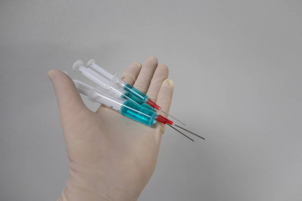istock 3 differently sized syringes filled with blue liquid are in one hand 1282985001