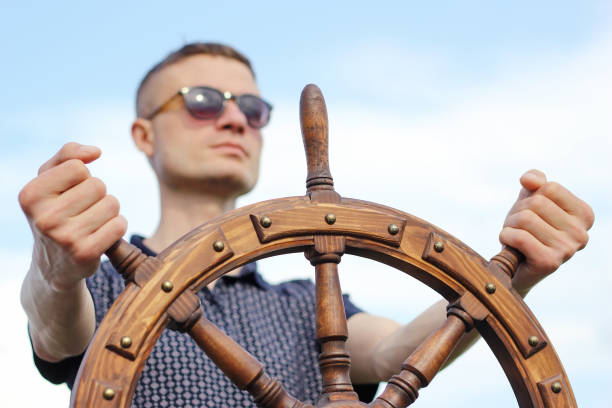 istock A man controls the yacht, hands on the steering wheel, handwheel on sky background 1282988064