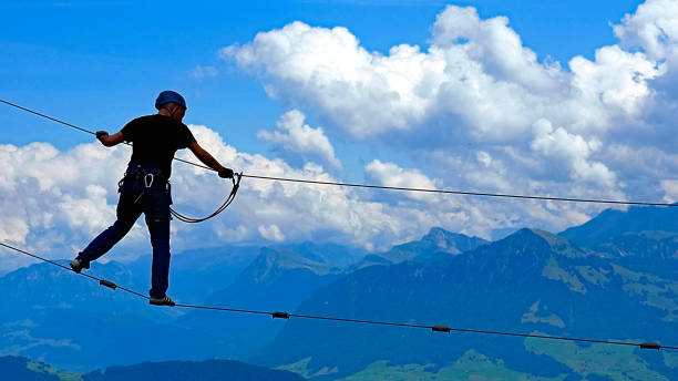 uomo che si bilancia su una corda nel parco di arrampicata con vista sulle alpi svizzere e cielo nuvoloso - skill vitality agility strength foto e immagini stock