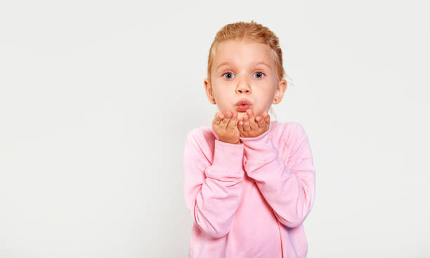 linda niña de 4-5 años enviando un beso. fondo blanco aislado. emociones de cerca, labios se inclinan. besando con la expresión de la cara de la ropa rosa. - facial expression small empty joy fotografías e imágenes de stock