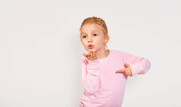 linda niña de 4-5 años enviando un beso. fondo blanco aislado. emociones de cerca, labios se inclinan. besando con la expresión de la cara de la ropa rosa. - facial expression small empty joy fotografías e imágenes de stock