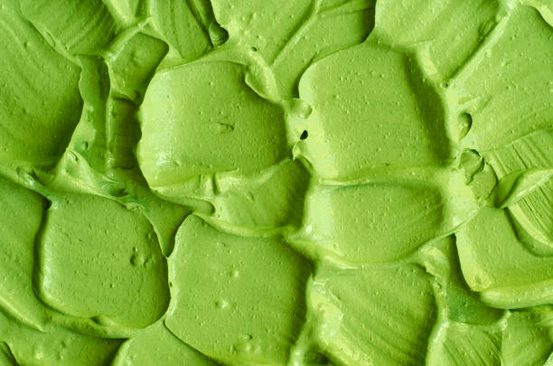 istock Green cosmetic clay (cucumber facial mask, avocado face cream, green tea matcha body wrap) texture close up, selective focus. Abstract background with brush strokes. 1282993572