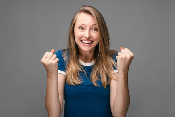 istock Successful Young female is smiling happily, making Winner gesture, standing gray background 1282995154