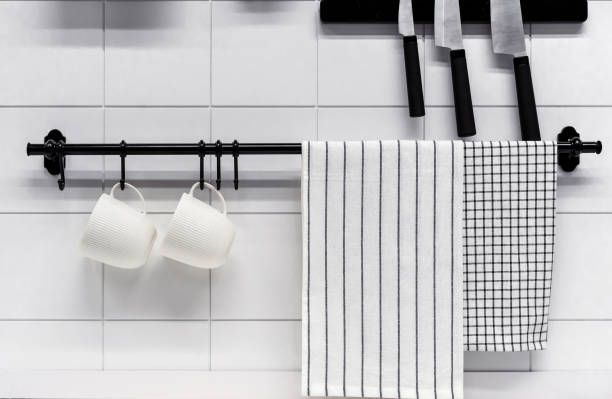 Two white mugs and two towels on a black kitchen rail.