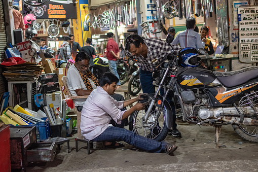 Nagpur, Maharashtra, India - March 2019: An Indian mechanic repairing a motorcycle at a pavement garage on the streets of the city.
