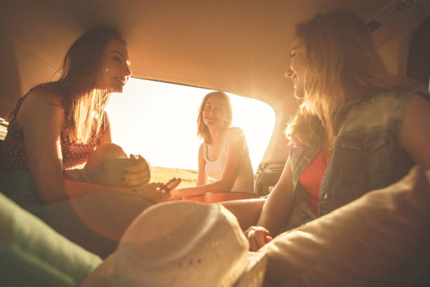 istock Girlfriends having fun in the car trunk while making a road trip during summer 1283004248
