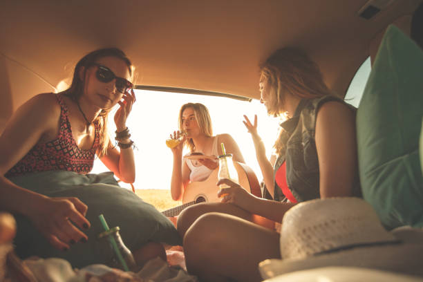 istock Female friends having fun in the car trunk while making a road trip 1283004252