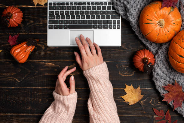 mãos femininas digitando laptop no espaço de trabalho com folhas de bordo amarelas e vermelhas - autumn women leaf scarf - fotografias e filmes do acervo