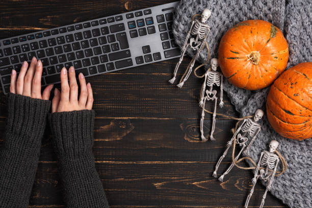 istock Female hands and Halloween decorations with skeleton and laptop 1283005528