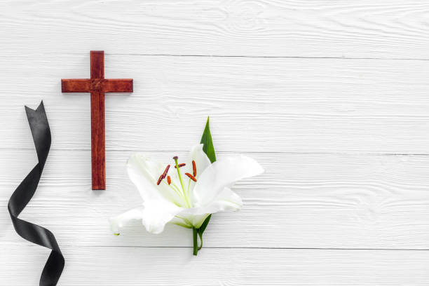 istock White lily with cross and black ribbon. Funeral concept 1283010956