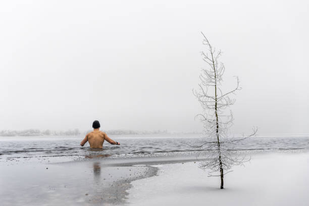 Young man taking bath in ice cold water and smiling.