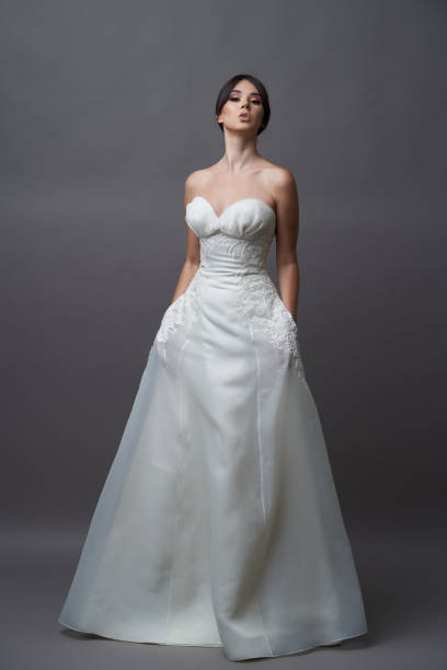 istock Beautiful bride in wedding dress posing on grey background with copy space. 1283014774