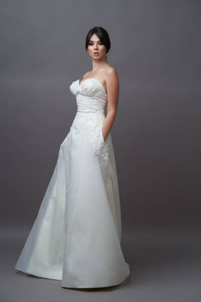 istock Beautiful bride in wedding dress posing on grey background with copy space. 1283014782