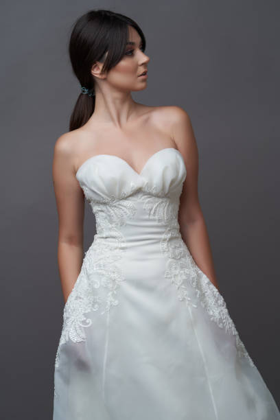 istock Beautiful bride in wedding dress posing on grey background with copy space. 1283014792